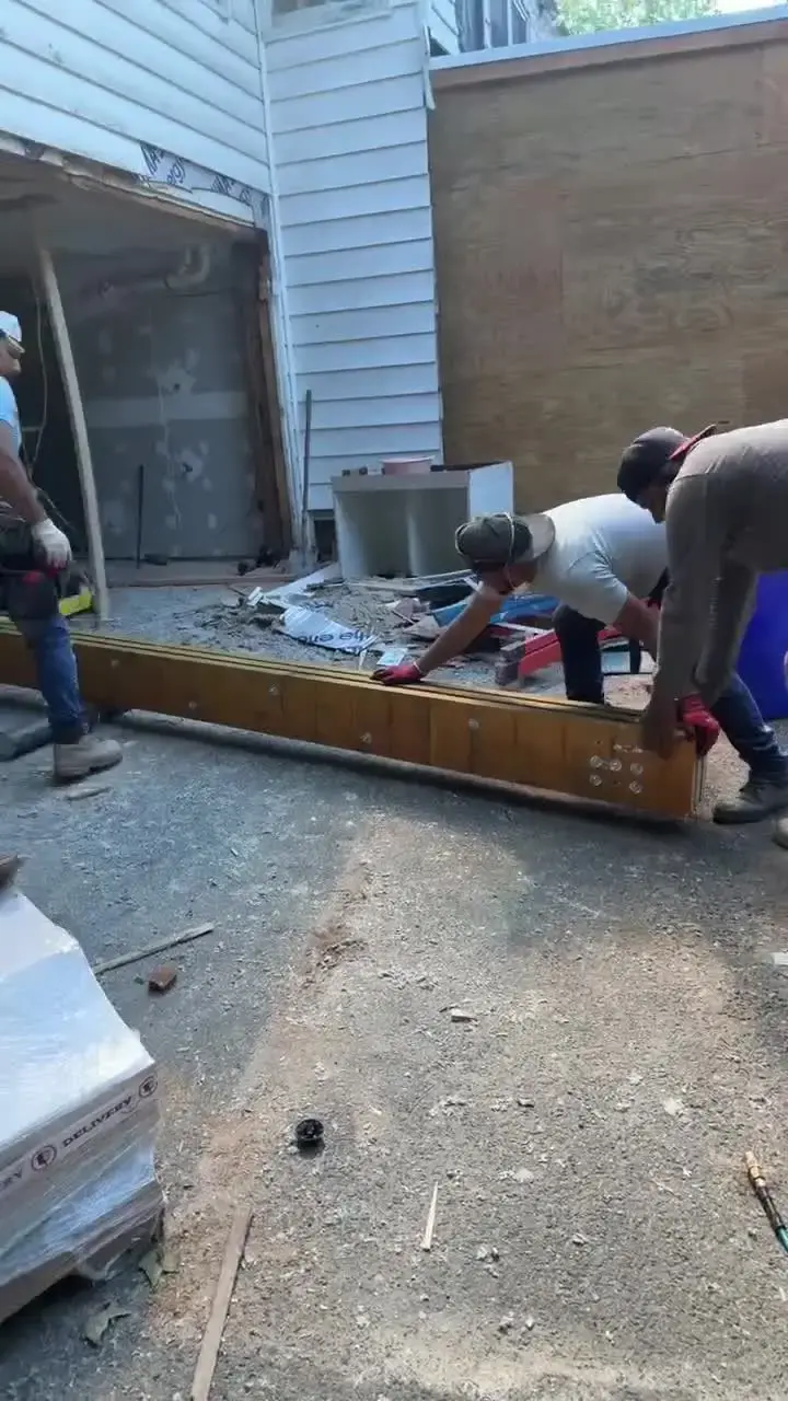 Crew setting a beam on the new addition foundation, job-site video