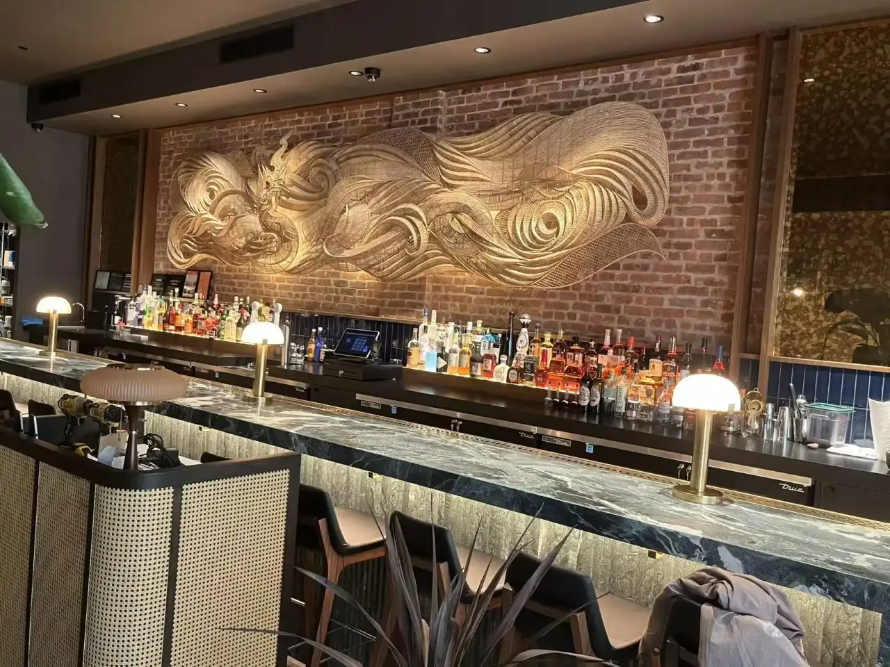 Bar with sculptural wall art, stone bar top and backlit shelving