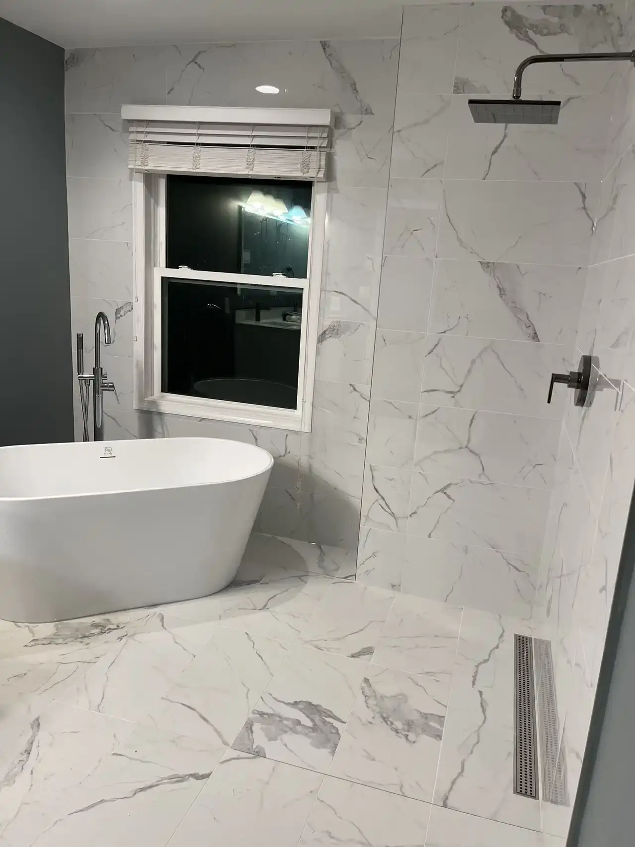 Primary bathroom with freestanding tub and marble-look porcelain tile