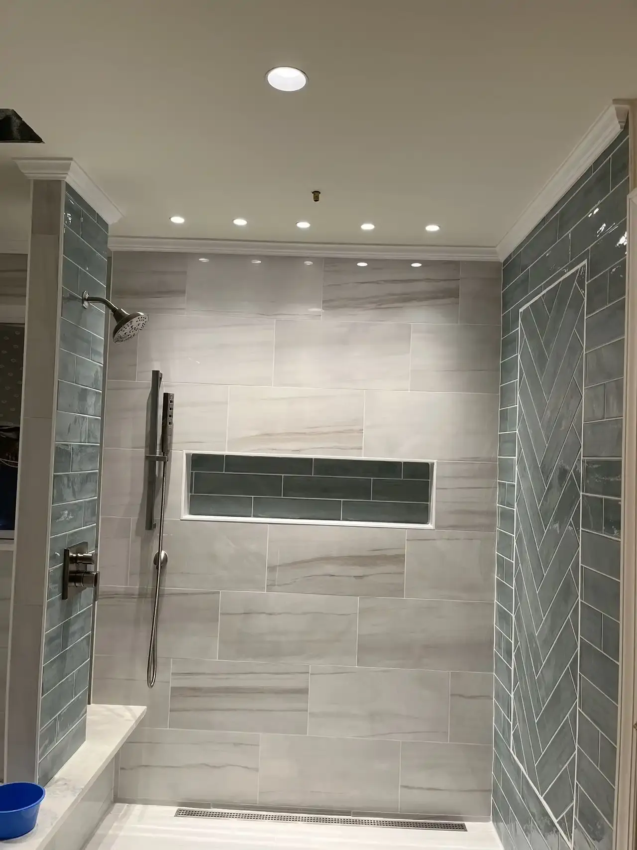Walk-in shower with linear drain, green accent tile and lit niche