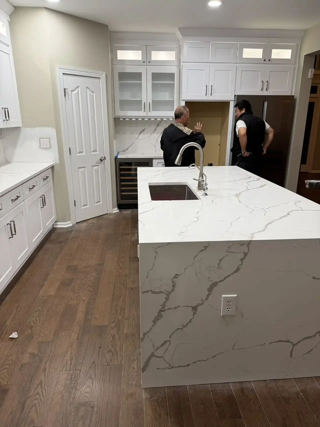 Open kitchen with waterfall quartz island and glass-front upper cabinets
